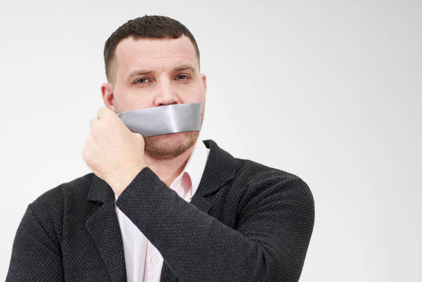 businessman is removing a piece of tape that has been covering his mouth - Photo, Image