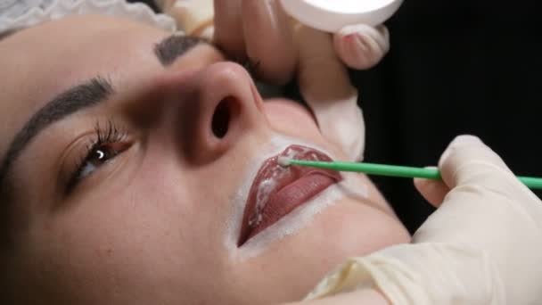 O mestre esteticista aplica anestesia especial aos lábios. Preparação para maquiagem permanente dos lábios. Tatuagem de rosto moderno
 - Filmagem, Vídeo