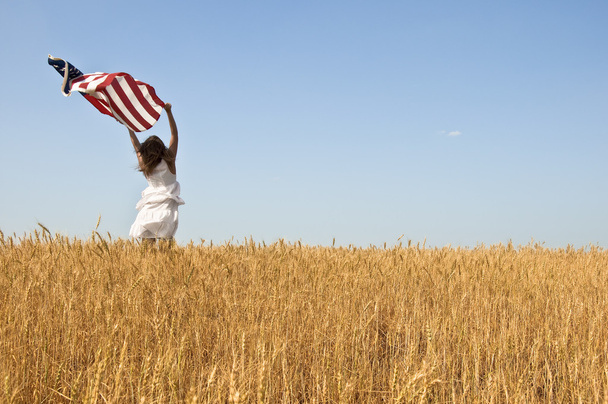 Woman holding a flag in a field of rye. - Фото, зображення