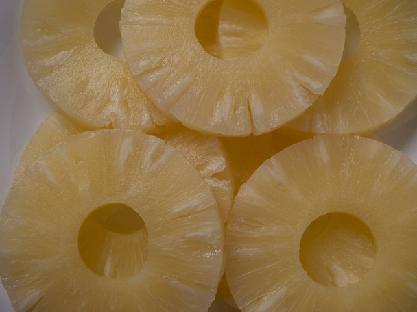 Amarillo jugosos anillos de piña en un plato blanco vista superior de cerca. Piña en conserva caramelizada picada. Dieta de alimentos crudos
. - Foto, Imagen
