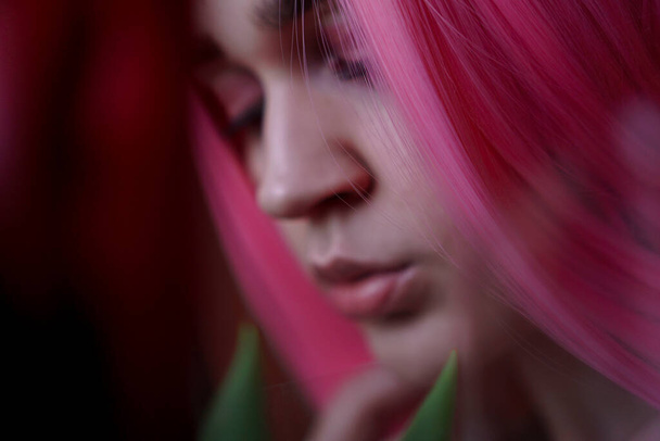 Girl with pink hair with flowers close to face. Out of focus, blurred background - Fotoğraf, Görsel