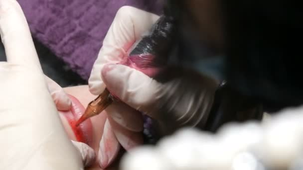 Tatouage à lèvres Microblading avec un pigment colorant rouge spécial qui corrige la couleur des lèvres dans une clinique de cosmétologie. Procédure permanente de maquillage des lèvres appliquant un maquillage pigmentaire sur les lèvres avec une machine à tatouer
 - Séquence, vidéo
