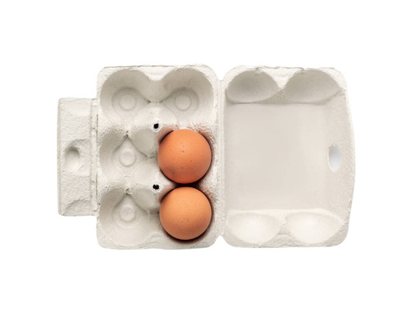 Open egg box with two brown eggs isolated on white background with clipping path. Fresh organic chicken eggs in carton pack or egg container top view - Photo, Image