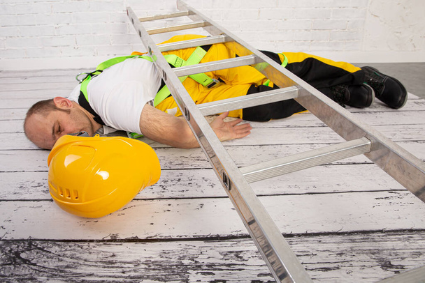Ein Bauunfall ist unvermeidlich, wenn wir die Arbeitsschutzbestimmungen nicht einhalten. Sturz von einer Leiter. - Foto, Bild