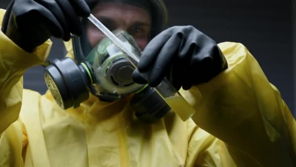 Homme avec équipement de protection mélange substance jaune dans le tube à essai
.  - Séquence, vidéo