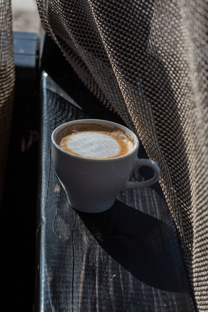 Kaffee selektiver Fokus. Weiße Tasse mit Cappuccino auf die Natur. Weiße Tasse mit Cappuccino, Kaffee, Morgen, Heiterkeit. - Foto, Bild