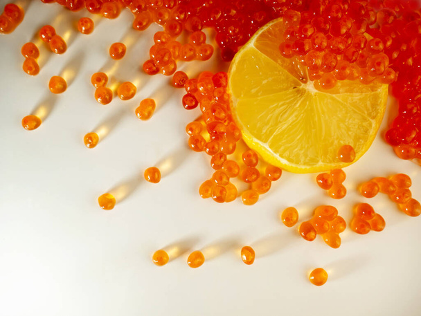 Red caviar with lemon on a light background. The view from the top. Seafood, delicacy - Photo, Image