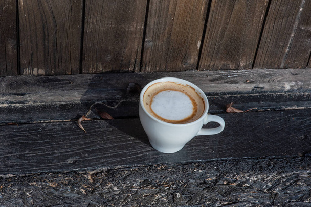 Koffie selectieve focus. Witte beker met cappuccino op de natuur. Witte beker met cappuccino, koffie, 's morgens, vrolijkheid. - Foto, afbeelding