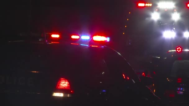 Policyjny samochód asystuje na miejscu wypadku samochodowego z holownikiem zabierającym pojazd w nocy. - Materiał filmowy, wideo