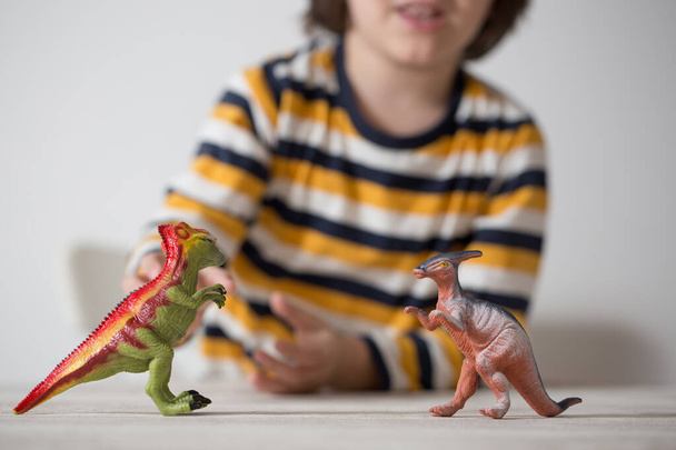 Bambino a casa a giocare con i dinosauri. Focus differenziale Fondo bianco. Concetto di infanzia
. - Foto, immagini