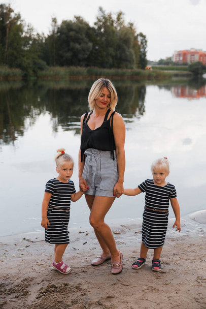 Familia de madre y dos niñas gemelas posa estanque parque
 - Foto, imagen