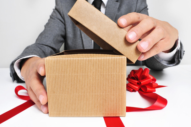 Человек в костюме открывает подарок
 - Фото, изображение