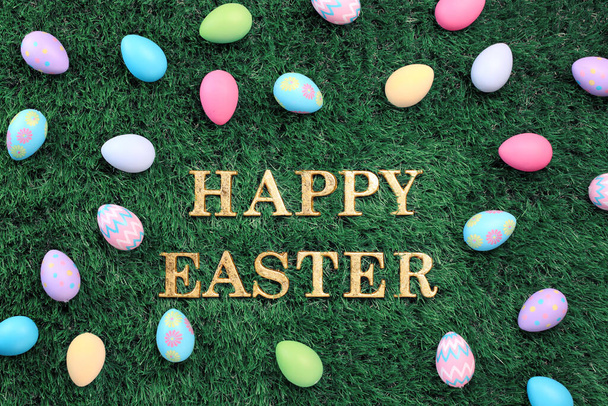 Gold Happy Easter text surrounded with colorful Easter eggs on grass - 写真・画像