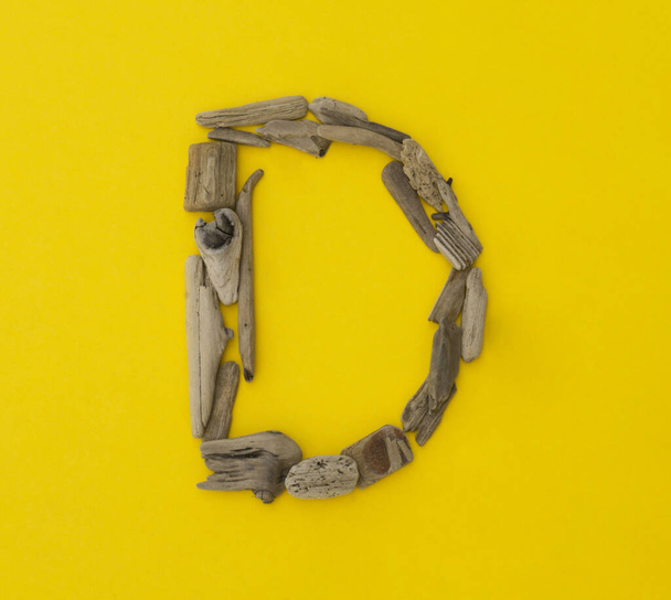 Colorful letter made of wooden sticks on yellow background. Many children's games. Find sea twig and shell. Learning school kindergarten. - Foto, imagen