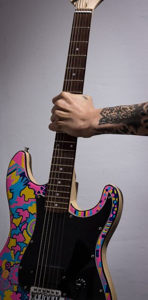 tetovált karját kezében egy színes gitár - Fotó, kép