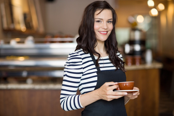 Beautiful Waitress Holding Coffee Cup In Cafeteria - Fotoğraf, Görsel