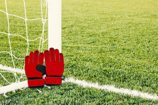 Kırmızı kaleci eldivenleri ve futbol kalesi arka planı. - Fotoğraf, Görsel