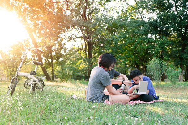 Joyeux famille assis sur l'herbe pour pique-nique au parc public
 - Photo, image