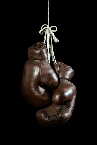 alte Boxhandschuhe, hängend, isoliert auf schwarzem Hintergrund - Foto, Bild