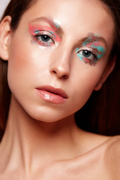 Beautiful girl with creative makeup. Young model with shining skin and long hair. Beauty face. Photo is taken in the studio. - Фото, изображение