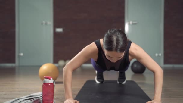 Jonge fitnessvrouw in sportkleding die push-up oefeningen doet thuis of in de studio. - Video