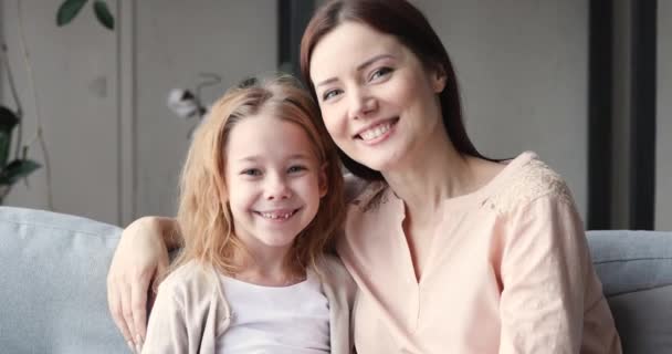 Affectionate young mother and small daughter bonding looking at camera - Materiał filmowy, wideo