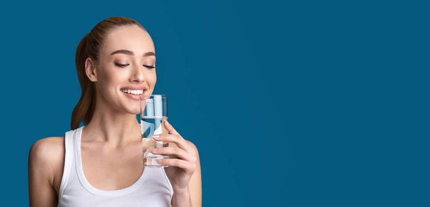 Mulher alegre bebendo água de vidro em pé, Studio Shot, Panorama
 - Foto, Imagem