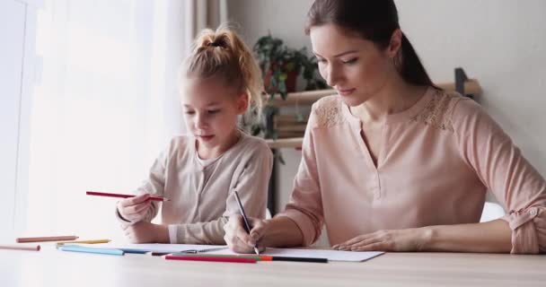 Happy mum helping kid daughter drawing colored pencils at home - Materiał filmowy, wideo