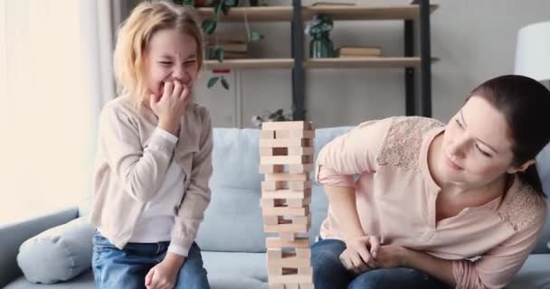 Cute funny small girl daughter playing jenga with young mom - Кадры, видео