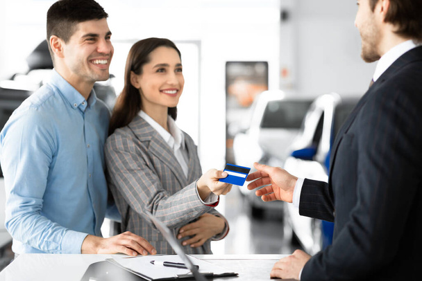 Couple Buying Car Giving Seller Credit Card In Dealership Office - Photo, Image