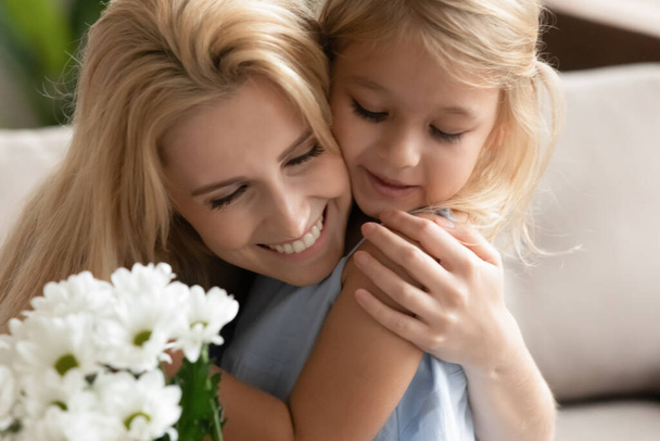 Маленька дочка вітає схвильовану маму з квітами
 - Фото, зображення