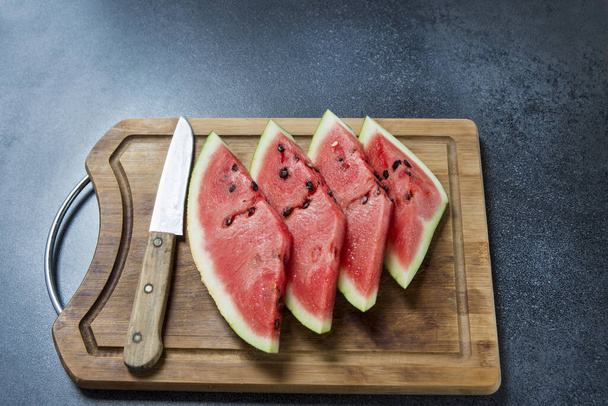 vier Wassermelonenscheiben auf dem Holz mit Messer - Foto, Bild