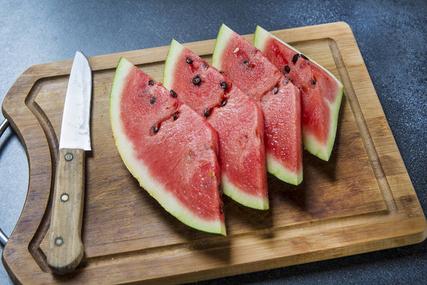 Wassermelonenscheiben mit dem Messer auf dem Holzbrett - Foto, Bild