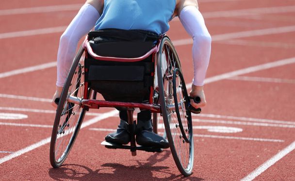 Atleta paralimpico in sedia a rotelle con paralisi alle gambe mentre corre veloce sulla pista durante la gara
 - Foto, immagini