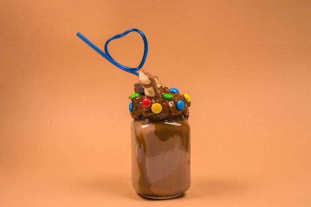 Шоколадный молочный коктейль со взбитыми сливками, печеньем, вафлями, подается в стеклянной банке. "Чокнутый или сумасшедший" сладкий коктейль. Пространство для текста или дизайна
. - Фото, изображение