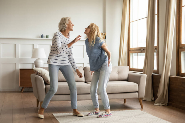 Overjoyed mature mother and adult daughter dance at home - Photo, image