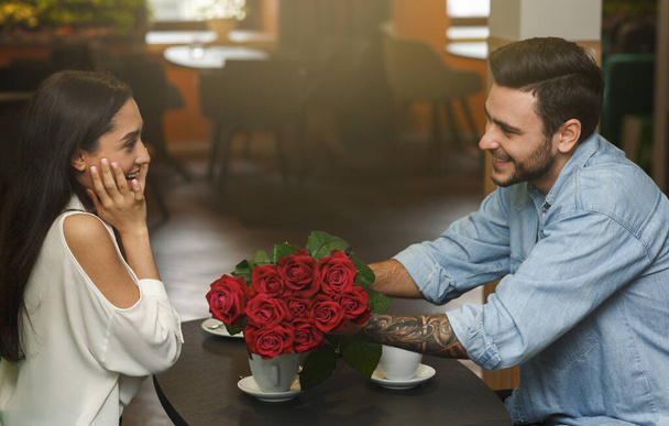 Novio dando sorpresa novia hermoso ramo de rosas en la cafetería
 - Foto, imagen