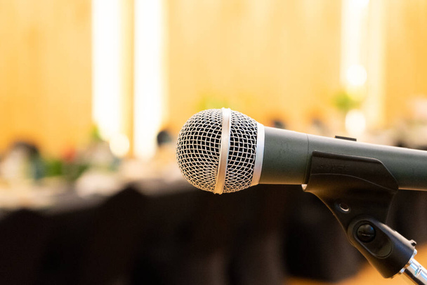 Közel a mikrofon mellett a pódium elmosódott hosszú fekete asztal vacsora ideje wolfram meleg fényben. - Fotó, kép