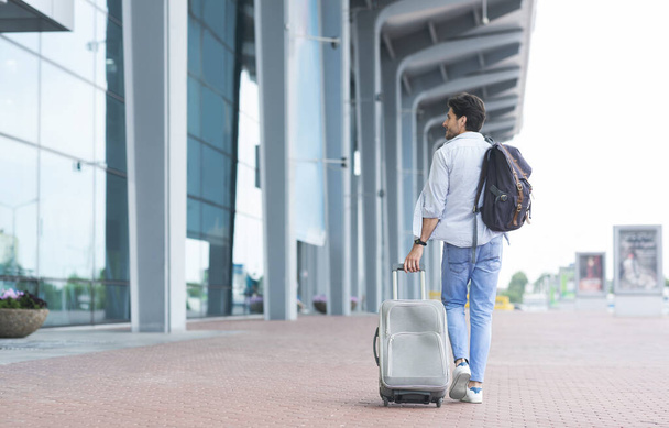 Homem viajante chegou ao aeroporto, andando com mala e mochila ao ar livre
 - Foto, Imagem