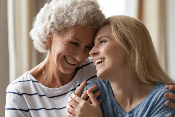 Happy senior mother and adult daughter embrace at home - Photo, Image