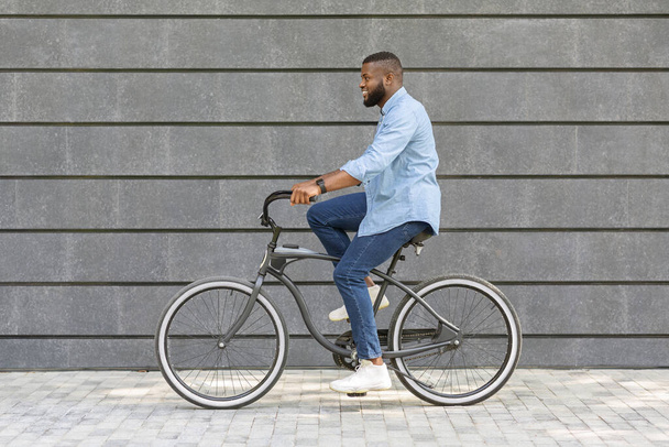 Camino a la oficina. Joven hombre de negocios afroamericano montando bicicleta al trabajo
 - Foto, Imagen