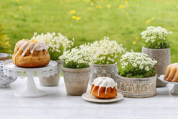 Traditional Easter cakes, beautiful spring flowers and handmade decoration made of moss and quail eggs. - Photo, image