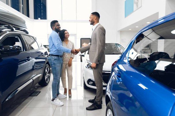 Happy Car Buyers poignée de main avec le vendeur debout dans la salle d'exposition concessionnaire
 - Photo, image