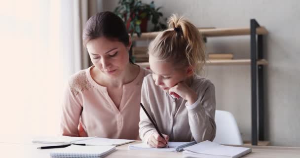 Cute small kid daughter learning writing with young mom - Záběry, video