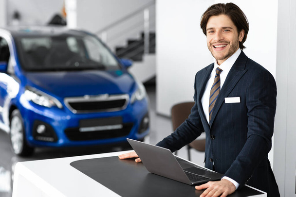 Πωλητής αυτοκινήτων που στέκεται σε πολυτελές γραφείο αντιπροσωπείας - Φωτογραφία, εικόνα