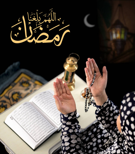 Chica musulmana levantando manos para orar sobre fondo negro, con caligrafía árabe Texto diciendo "Dios, ayúdanos a llegar al Ramadán
" - Foto, imagen
