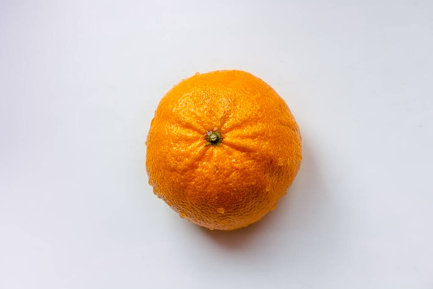 мандарин с капельками воды в центре рамки на белом фоне
 - Фото, изображение