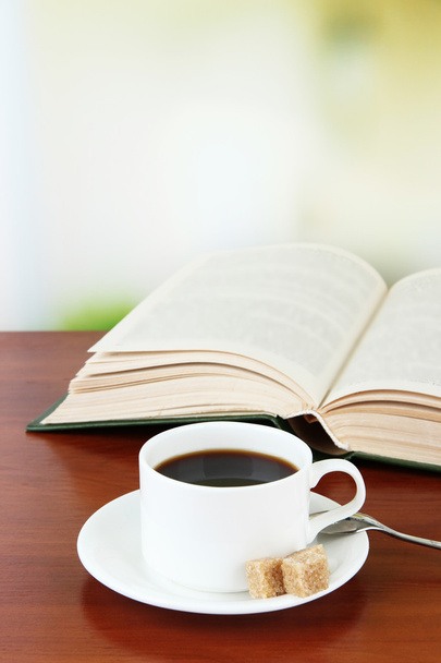 Cup of coffee with sugar and book on wooden table bright background background - 写真・画像