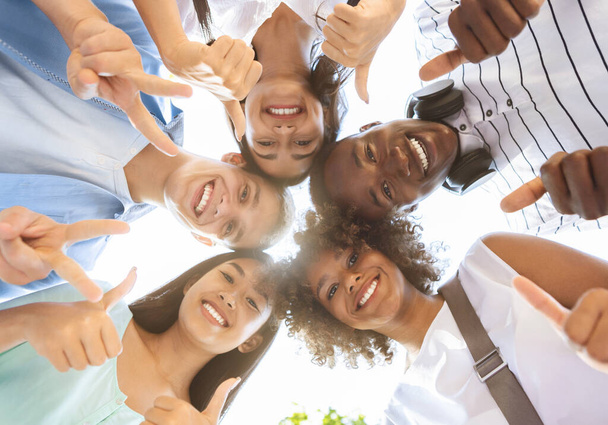 Radostné multikulturní teenageři stojící v kruhu, ukazuje legrační gesta, nízký úhel - Fotografie, Obrázek