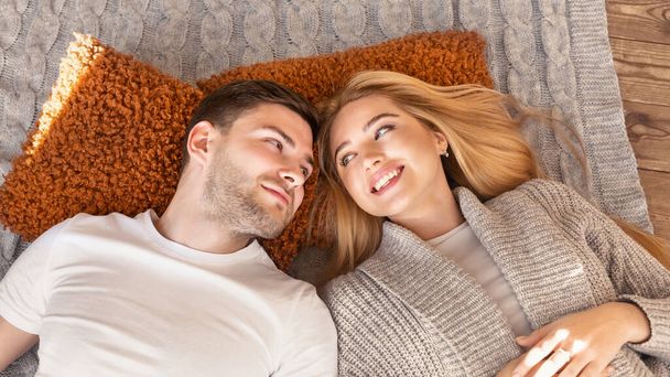 Χαμογελώντας παντρεμένο ζευγάρι ξαπλωμένο μαζί στο πάτωμα στο σπίτι, πάνω από την θέα. Πανόραμα - Φωτογραφία, εικόνα